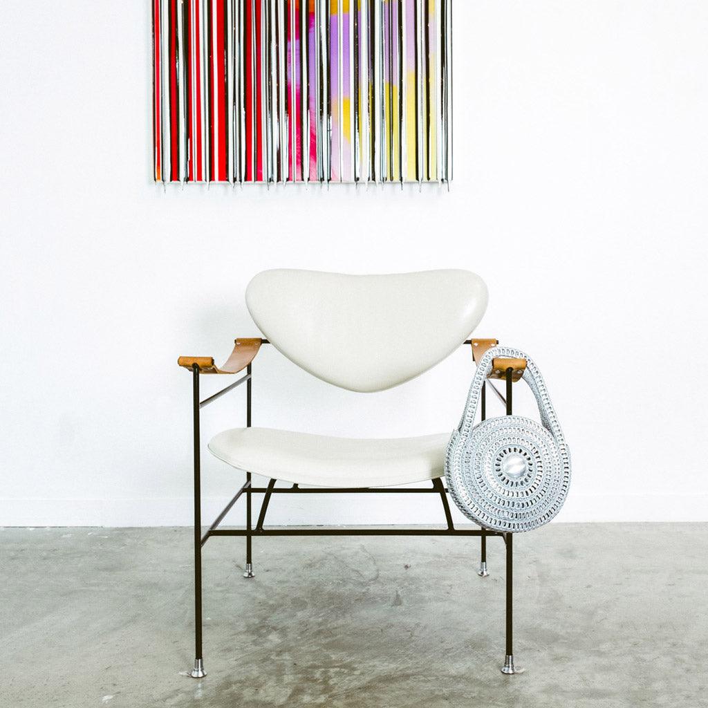 alt="silver metal circle purse hanging on arm of chair, Escama Studio"