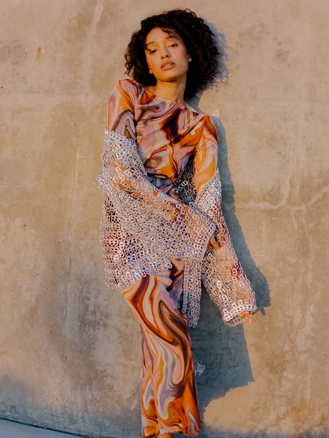 woman in orange swirl dress and silver metallic jacket made of pop tabs - escama studio