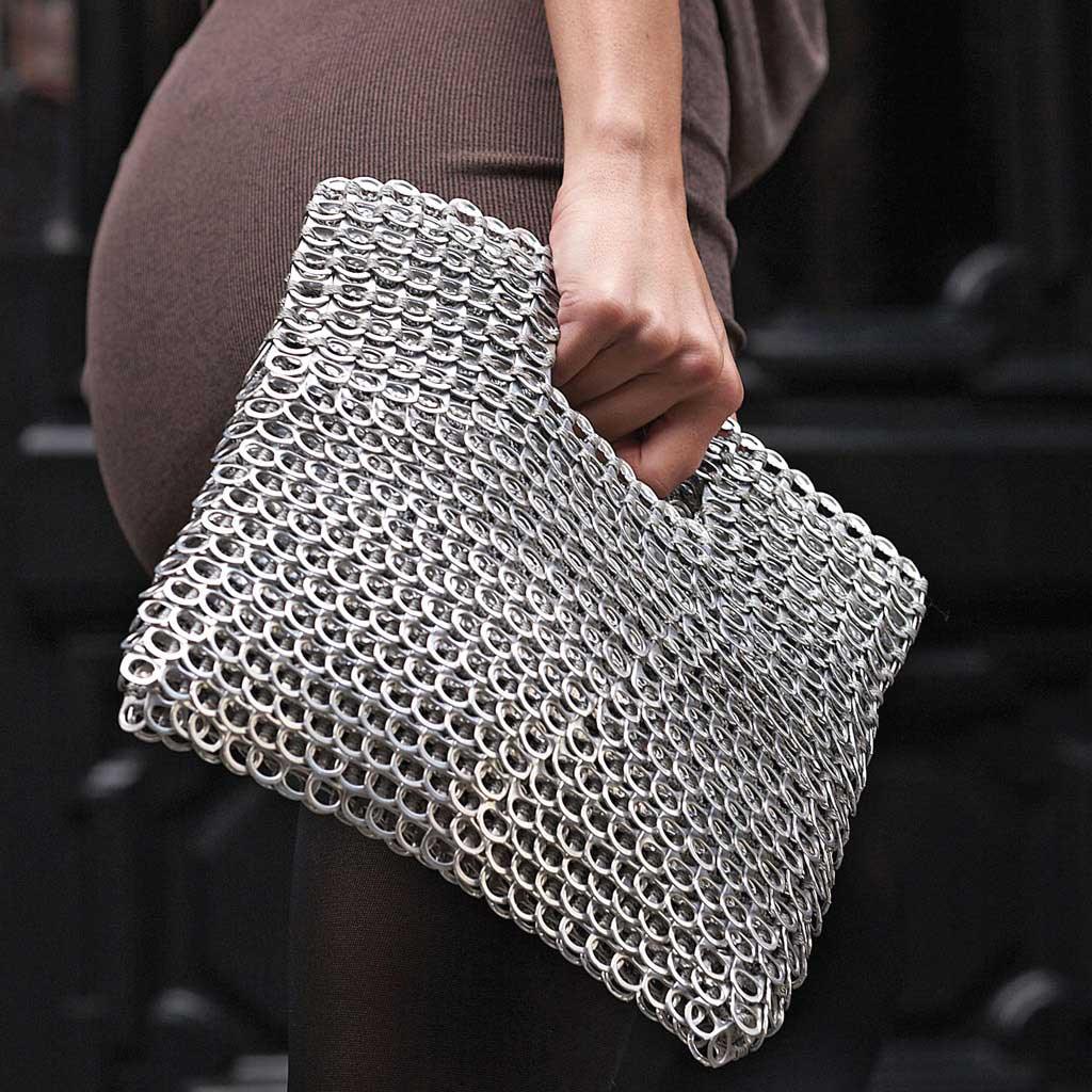 alt="silver clutch purse with cut out handle held by woman, Leda bag by Escama Studio"